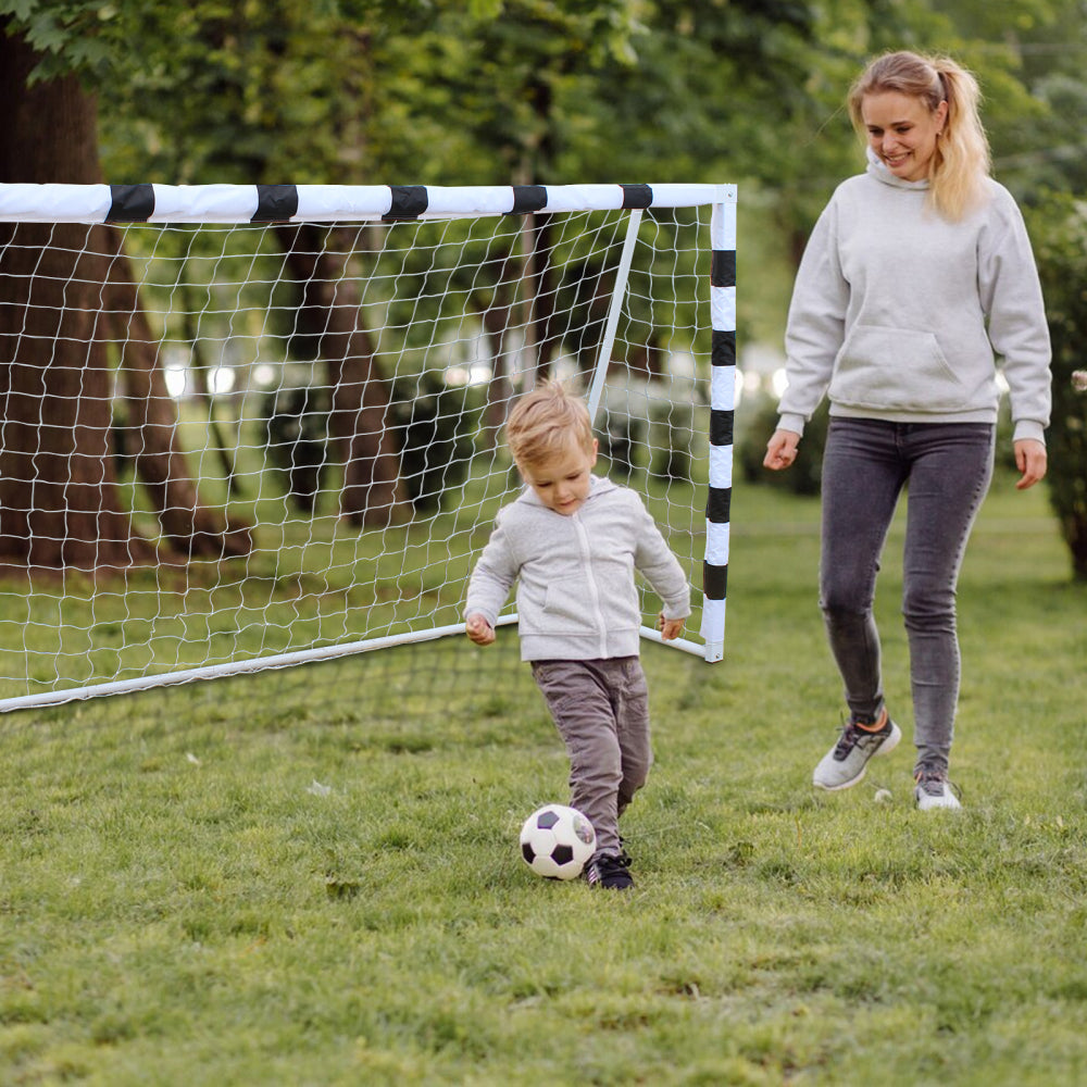 Mutter und Kind spielen gemeinsam Fußball im Garten mit dem großen, tragbaren Fußballtor.