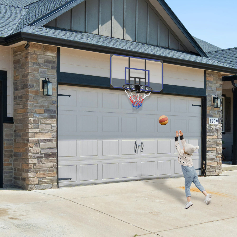 Basketballkorb montiert über einem Garagentor an einer Außenfassade, Kind wirft einen Ball.