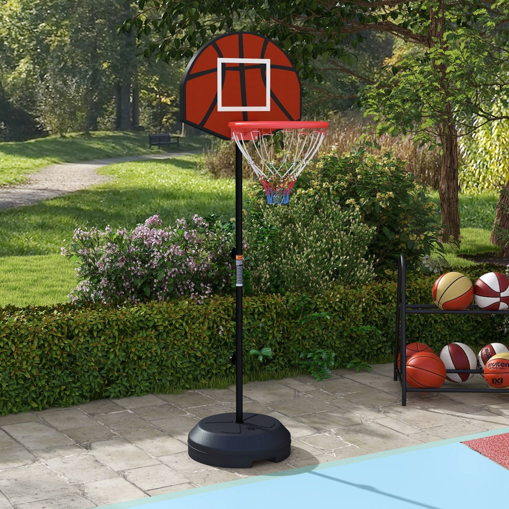 Basketballständer im Garten auf einer Terrasse, umgeben von Hecken und Spielbällen.