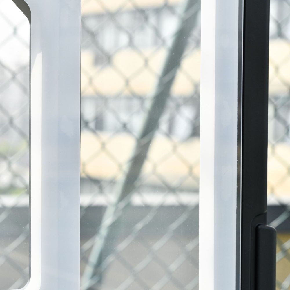 Blick durch einen Zaun auf den stabilen Basketballpfosten und das Netz.