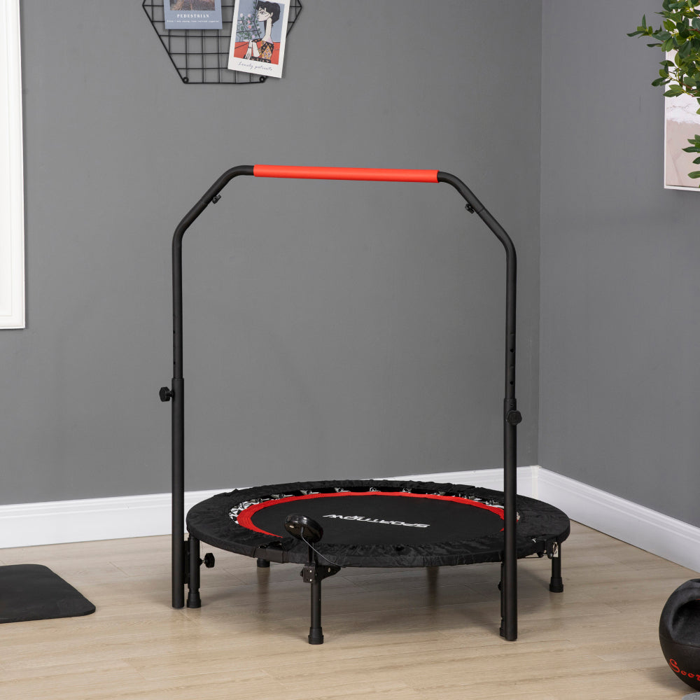 Das schwarze Trampolin mit roten Akzenten steht einsatzbereit in einem modernen grauen Zimmer.