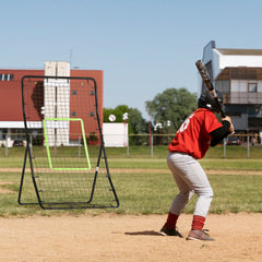 Ein Baseballspieler in Uniform nutzt die Rückprallwand auf einem Sportplatz zum Wurftraining.