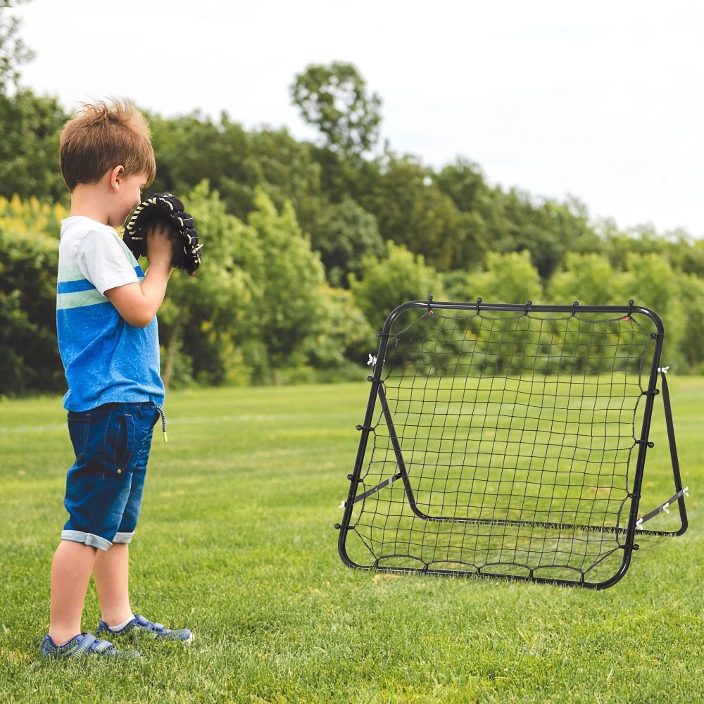 Ein kleiner Junge übt mit dem Rebounder auf einer grünen Wiese seine Ballkontrolle.