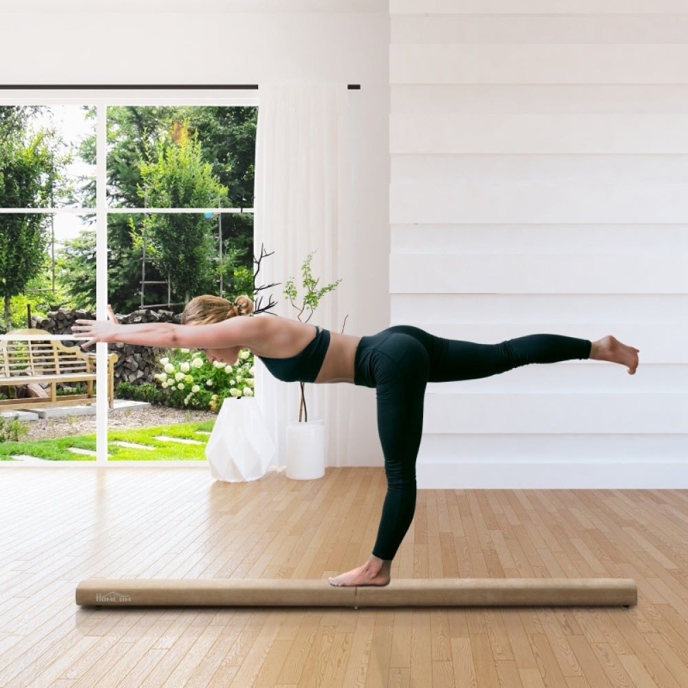 Eine Turnerin führt eine elegante Standwaage auf dem braunen Schwebebalken in einem modernen Wohnzimmer aus.