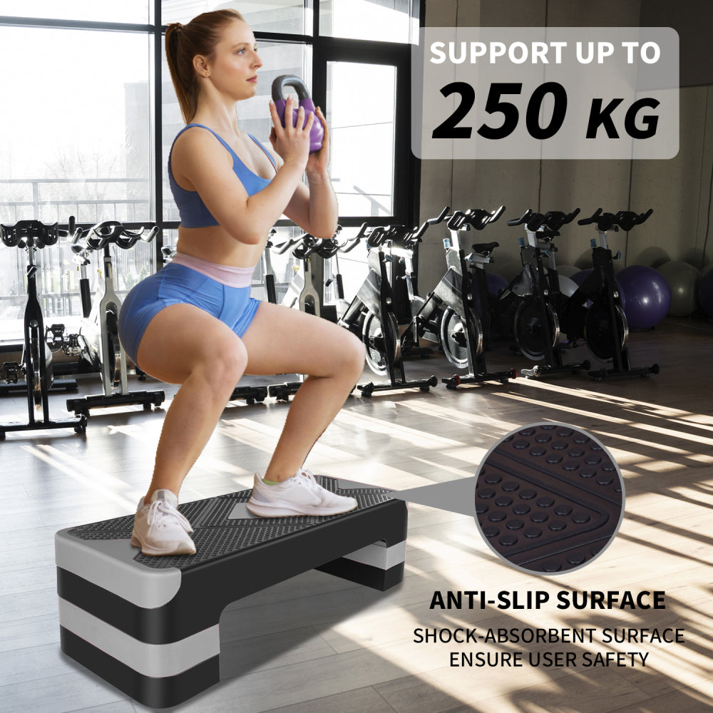 Frau beim Krafttraining (Kniebeugen mit Gewicht) auf dem Stepper (bis 250 kg belastbar).