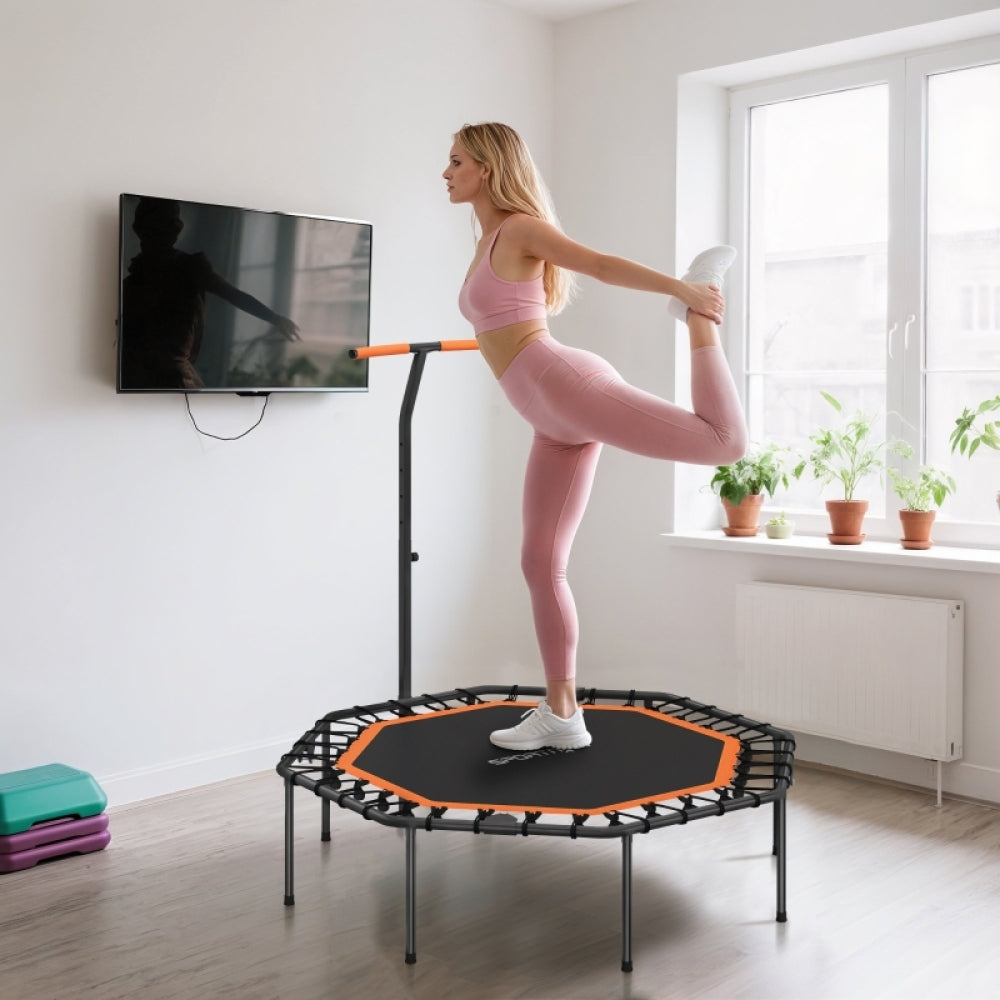 Frau dehnt sich nach dem Training auf dem Trampolin im hellen Wohnzimmer.