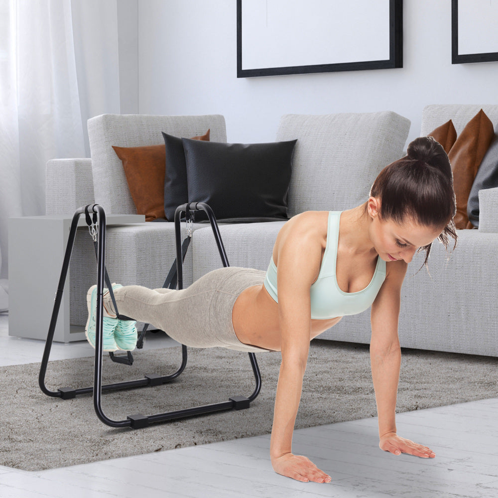 Frau führt eine Core-Übung aus, indem sie ihre Füße in die Schlaufen des Schlingentrainers einhängt.
