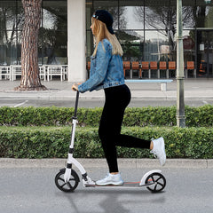 Frau fährt mit dem Cityroller auf einem gepflasterten Weg in der Stadt.