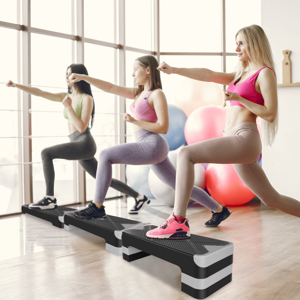 Frauengruppe beim gemeinsamen Step-Aerobic-Kurs im Fitnessstudio.