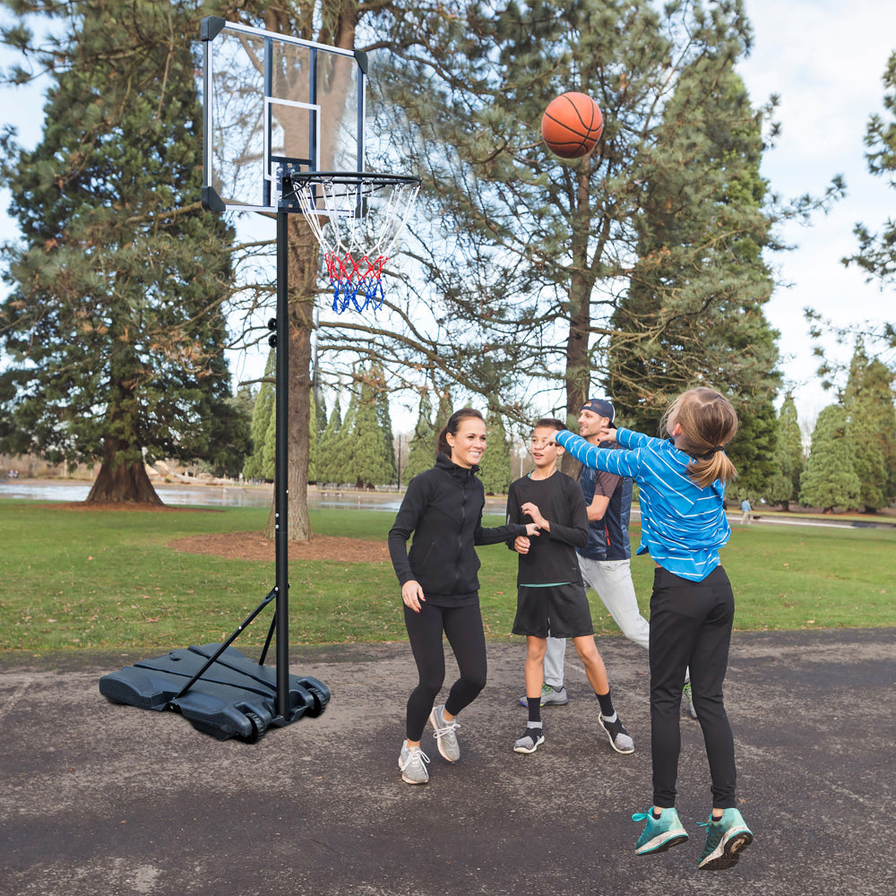 Gruppe von Kindern spielt Basketball im Park mit dem mobilen Basketballständer.