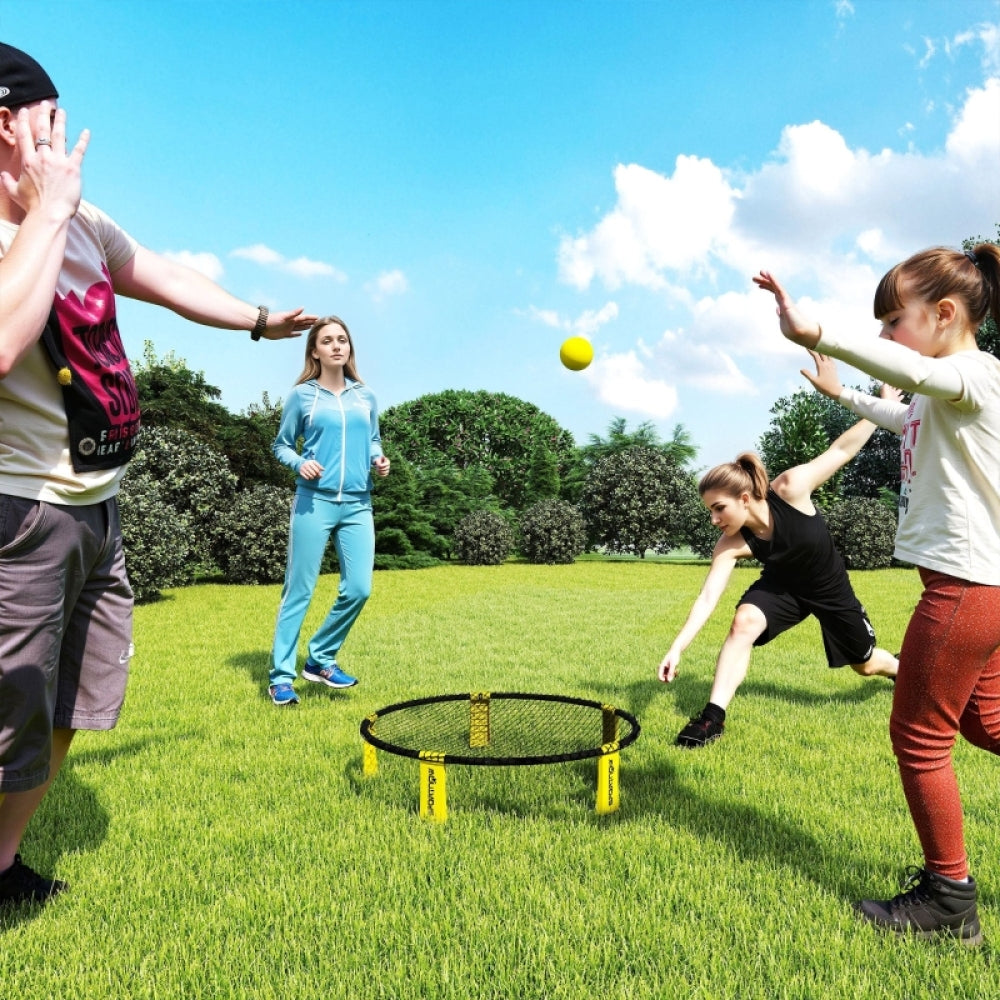 Jugendliche spielen begeistert Roundnet auf einer grünen Wiese unter blauem Himmel.