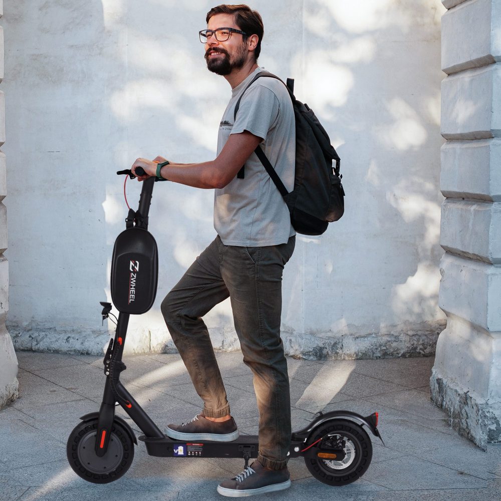 Mann trägt den E-Scooter lässig über der Schulter im Freien.