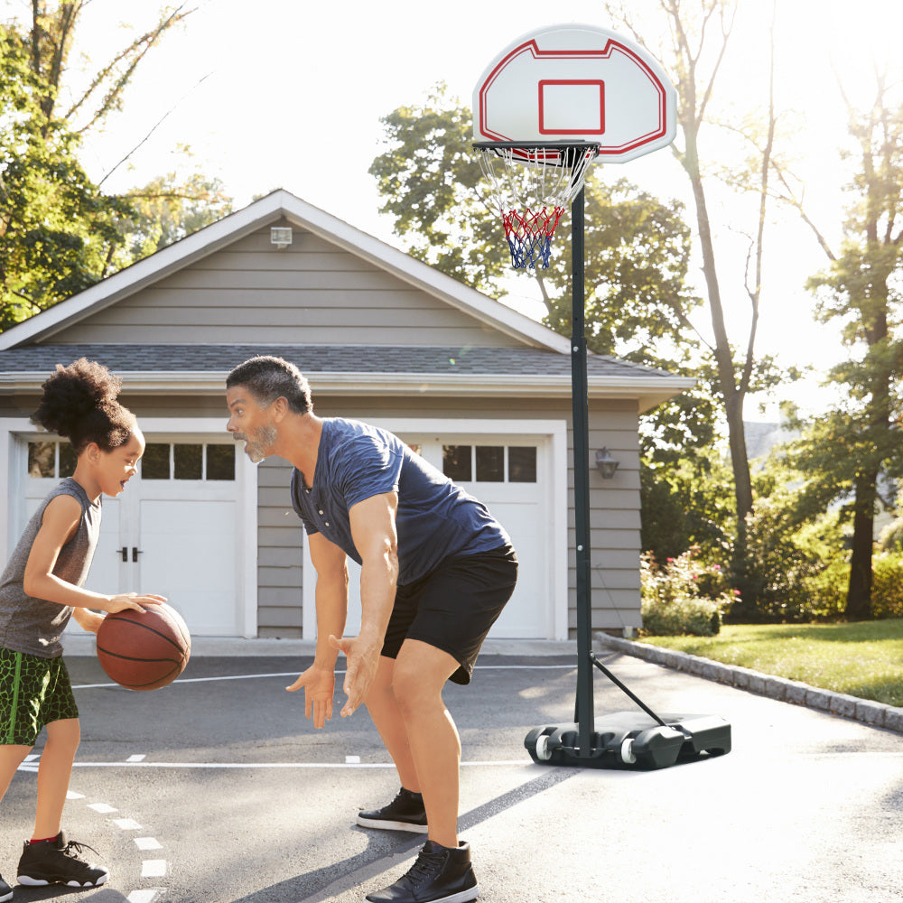 Vater und Tochter spielen Basketball in der Einfahrt vor dem Garagentor.