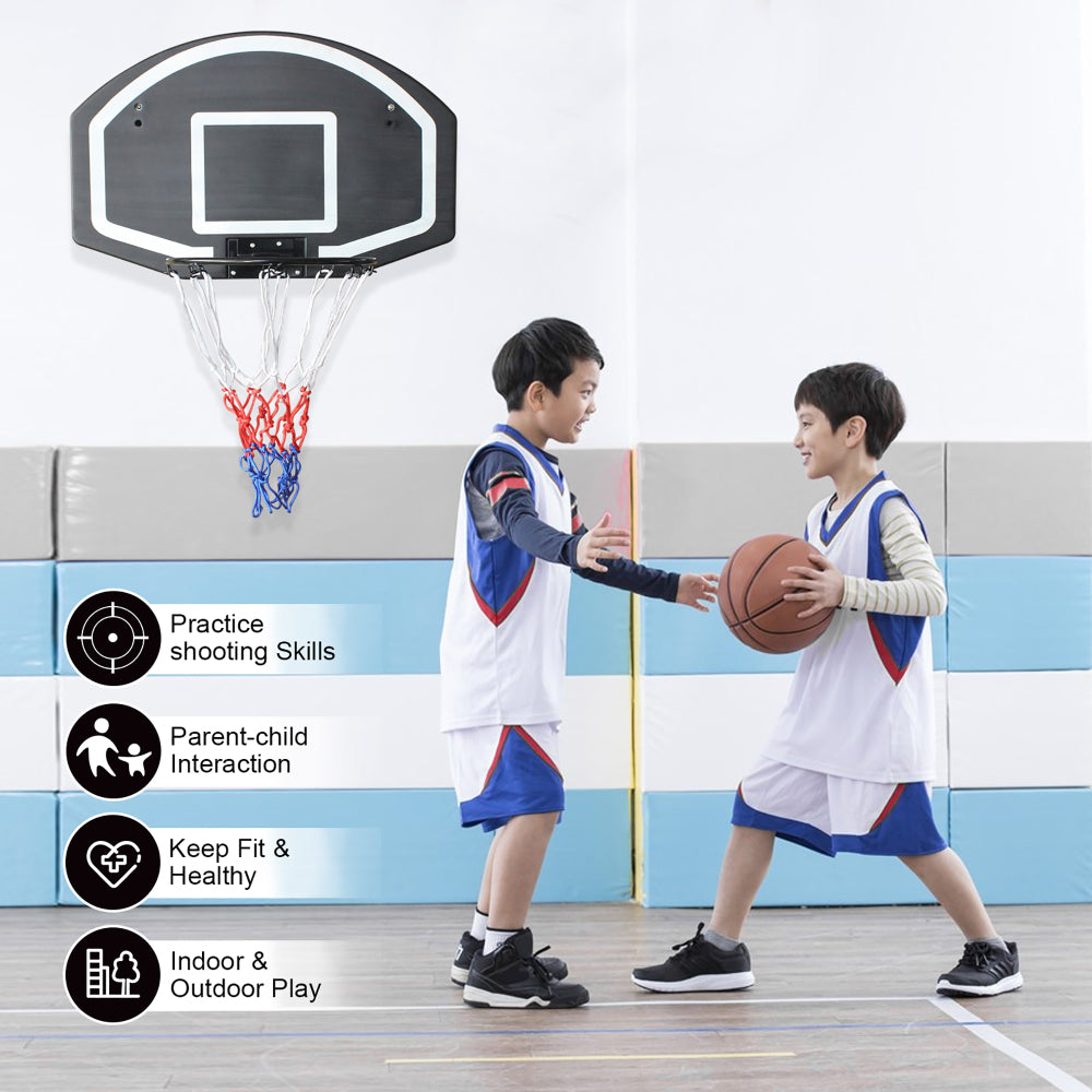 Zwei Jungen spielen Basketball im Innenraum an einer weißen Wand.