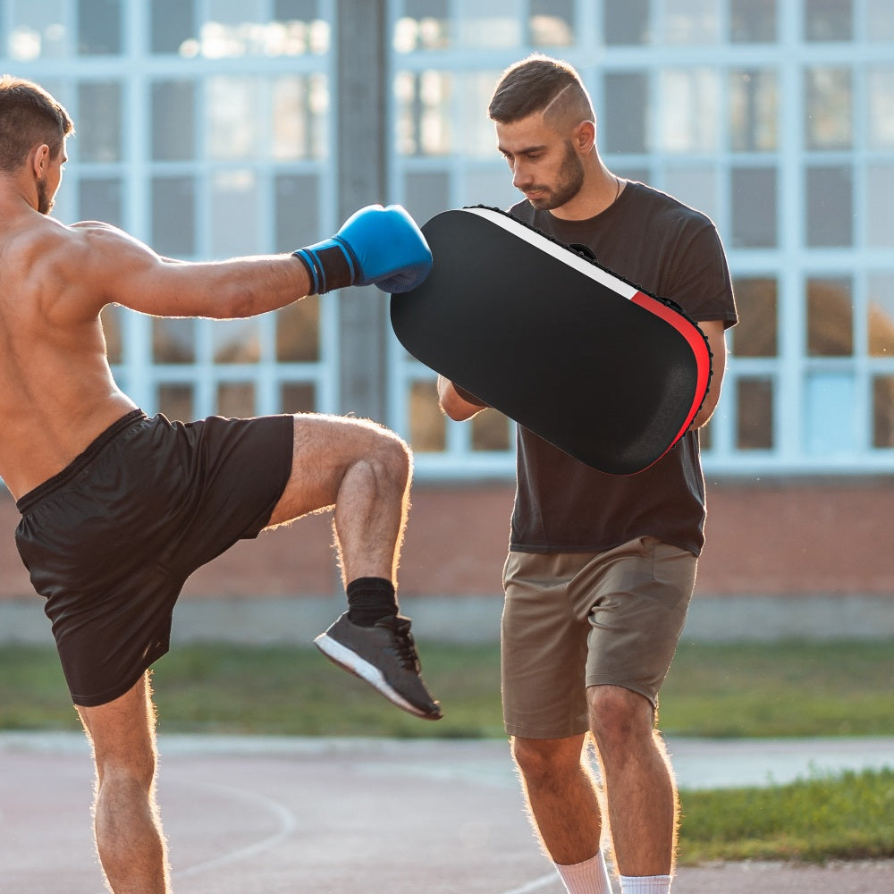 Zwei Männer beim Kickbox-Training: Trainer hält zwei Pratzen für einen Low-Kick des Partners.